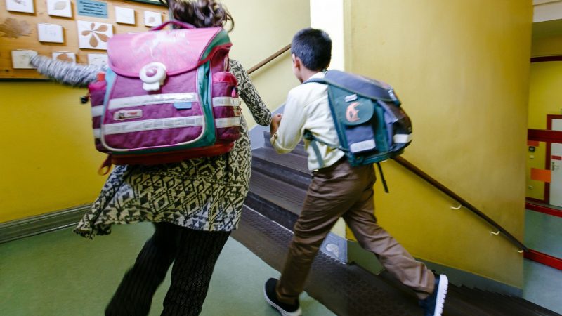 Zwei Kinder laufen durch das Treppenhaus ihrer Grundschule.
