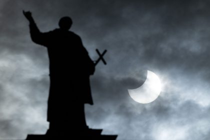 Bei einer partiellen Sonnenfinsternis wird die Sonne teilweise vom Mond verdeckt. Im Vordergrund ist eine Mattielli-Statue auf der Katholischen Hofkirche in Dresden zu sehen.