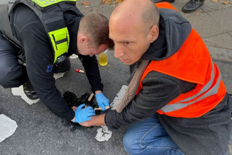 Ein Polizist (L) versucht die Hand eines Mannes, der sich auf die Straße geklebt hat, zu lösen, während Klimaaktivisten der Bewegung „Last Generation“ am 17. Oktober 2022 in Berlin gegen fossile Brennstoffe demonstrieren. Foto: Odd Andersen/AFP via Getty Images