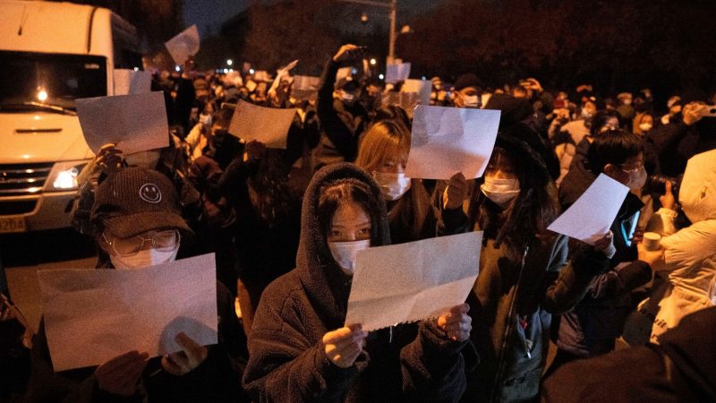 Demonstrierende in Peking halten leere Papiere hoch. In China hat die strenge Corona-Politik am Wochenende zu den größten Protesten seit Jahrzehnten geführt.