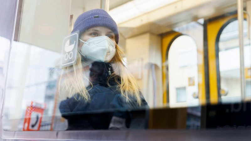 Eine junge Frau sitzt in einer Straßenbahn der SSB in Stuttgart. Die digitale Gesundheitsministerkonferenz der Länder berät über die Zukunft der Maskenpflicht.