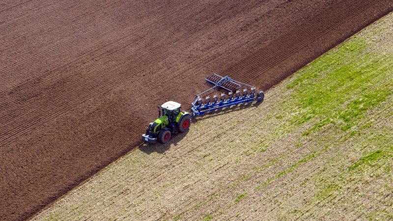 Ein Landwirt pflügt ein abgeerntetes Feld und bereitet es für die Neubestellung vor.