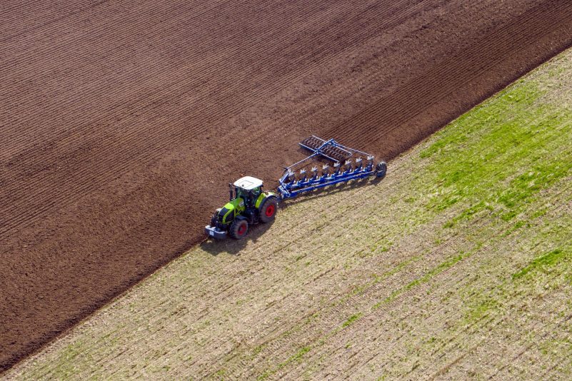 Ein Landwirt pflügt ein abgeerntetes Feld und bereitet es für die Neubestellung vor.