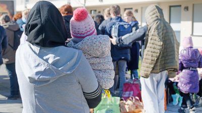 Aus der Ukraine vertriebene Menschen stehen mit ihrem Gepäck vor einem Flüchtlingsheim in Köln.