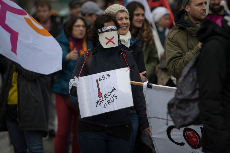 Eine Teilnehmerin einer Demonstration gegen Frankreichs umstrittene Rentenreform mit einem und dem Wortspiel «Macrona Virus» (Archivbild).