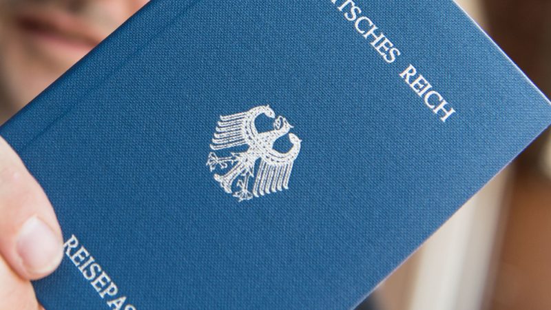 Ein Mann hält ein Heft mit dem Aufdruck «Deutsches Reich Reisepass» in der Hand. Sogenannte Reichsbürger leugnen die Existenz der Bundesrepublik Deutschland.
