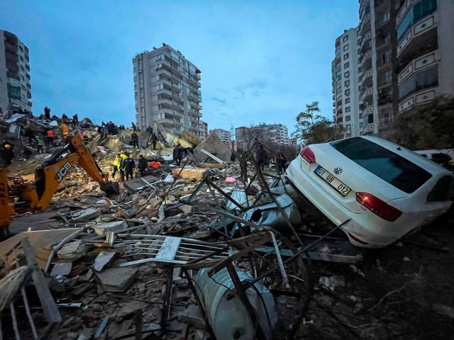 Notfallteams suchen nach Menschen in einem zerstörten Gebäude, während ein Auto auf den Trümmern liegt. Nach mehreren schweren Erdbeben in der türkisch-syrischen Grenzregion ist die Zahl der Toten auf mehr als 1900 gestiegen.