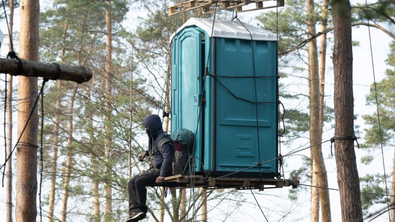 Ein Aktivist der Initiative «Heibo bleibt» sitzt an einem mit Seilen befestigten Dixi-Klo. Das besetzte Waldgebiet ist in der Laußnitzer Heide.