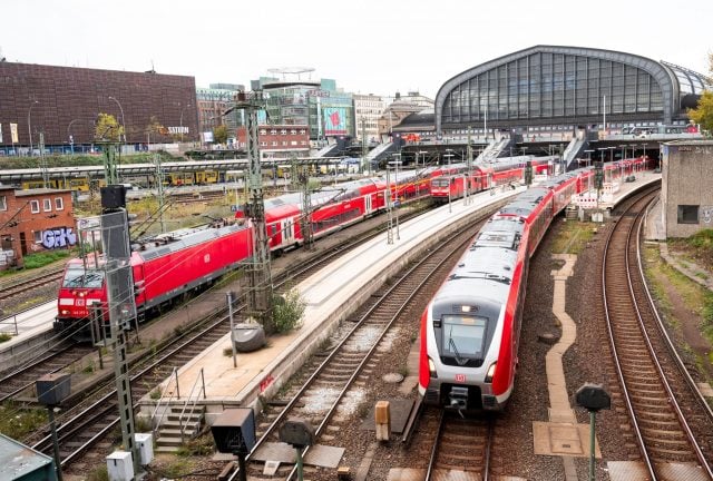 Eine S-Bahn fährt aus dem Hauptbahnhof in Hamburg aus. Daneben stehen zwei Regionalzüge der Deutschen Bahn.