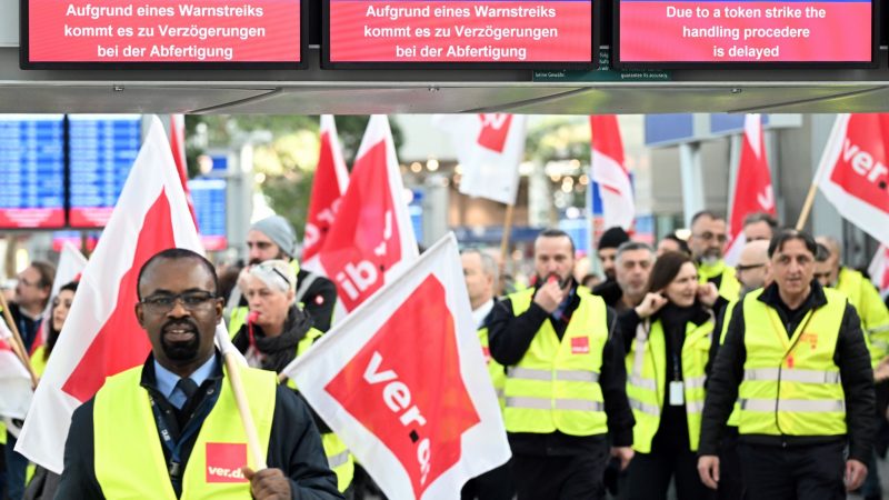 Streikende Mitarbeiter stehen mit Verdi-Flaggen im Terminal des Flughafens Düsseldorf.