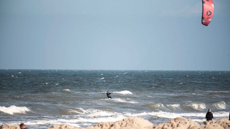 Ein Windsurfer surft auch bei kalten Temperaturen durch die Wellen am Ostseestrand von Warnemünde in Mecklenburg-Vorpommern.