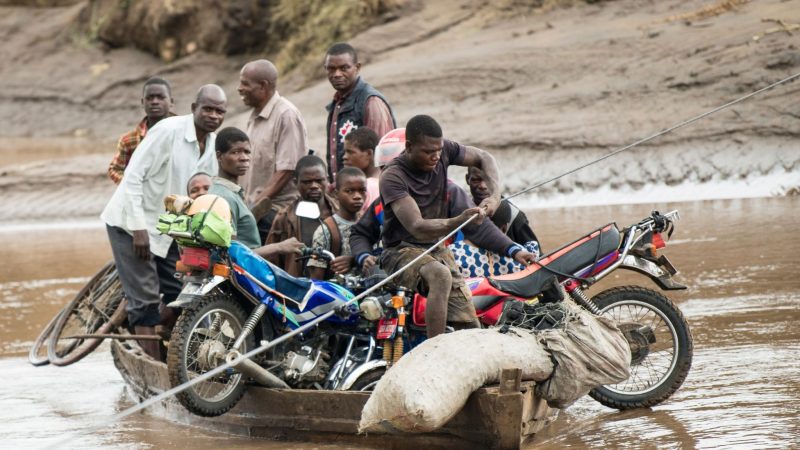 Männer transportieren in Malawi ihre geretteten Habseligkeiten mit einem Holzboot.