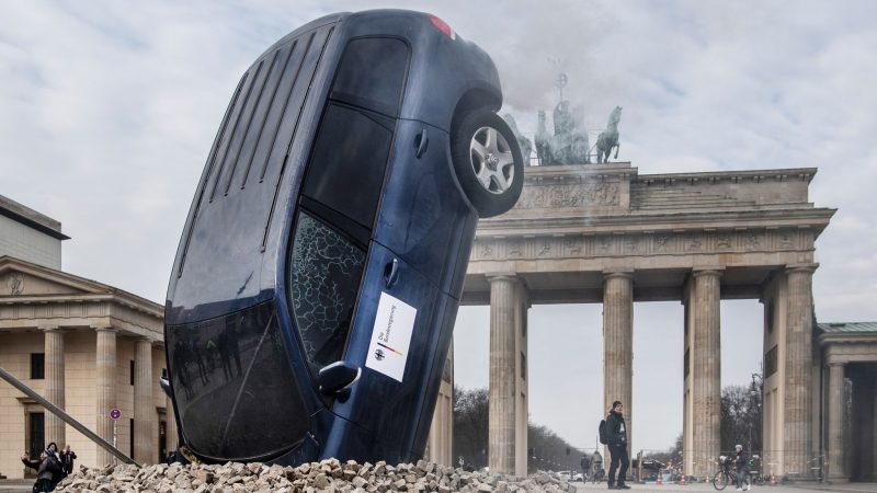 Was ist denn hier passiert? Ein SUV steckt scheinbar im Boden vor dem Brandenburger Tor, aus dem Heckbereich steigt Qualm. Nein, dieses Auto ist nicht vom Himmel gefallen. Es ist eine Aktion der Umweltschutz-Aktivisten von Greenpeace.