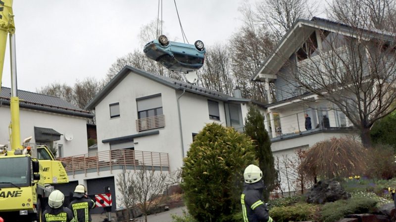 Ein Kranwagen hebt den verunglückten Kleinwagen von der Terrasse und dem Garten eines Einfamilienhauses in Gummertsbach.