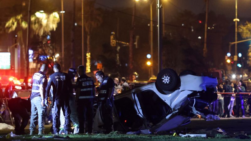 Polizei und der Rettungsdienst stehen nahe des Strands von Tel Aviv neben dem Auto, das sich überschlagen hat.