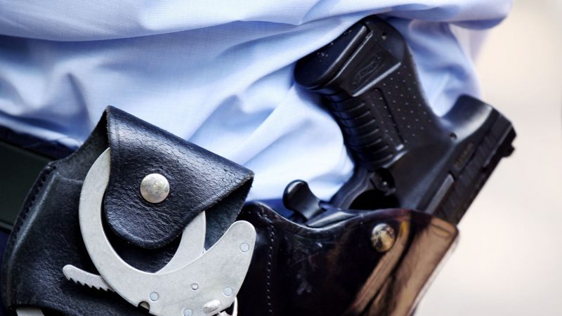 Ein Polizist mit Handschellen und Pistole am Gürtel.