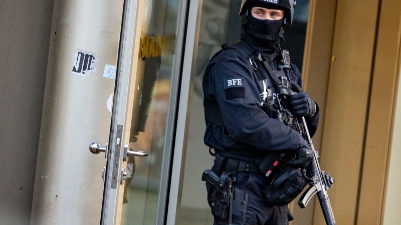Ein Polizist steht mit einer Maschinenpistole in Duisburg. Bei einer Attacke in einem Fitnessstudio in der Innenstadt sind mehrere Personen schwer verletzt worden.