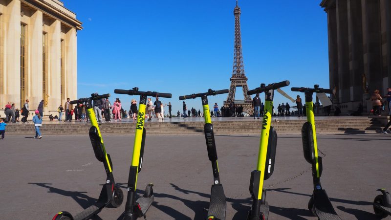 E-Tretroller zum Mieten stehen auf der Place du Trocadero in Paris, im Hintergrund ist der Eiffelturm zu sehen.