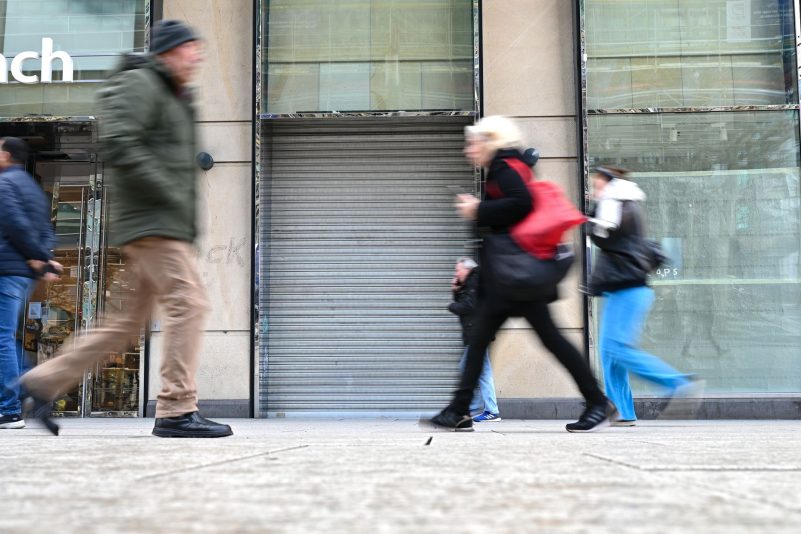 Passanten gehen auf der Einkaufsmeile Zeil in Frankfurt/Main an einem leerstehenden Geschäft vorbei.