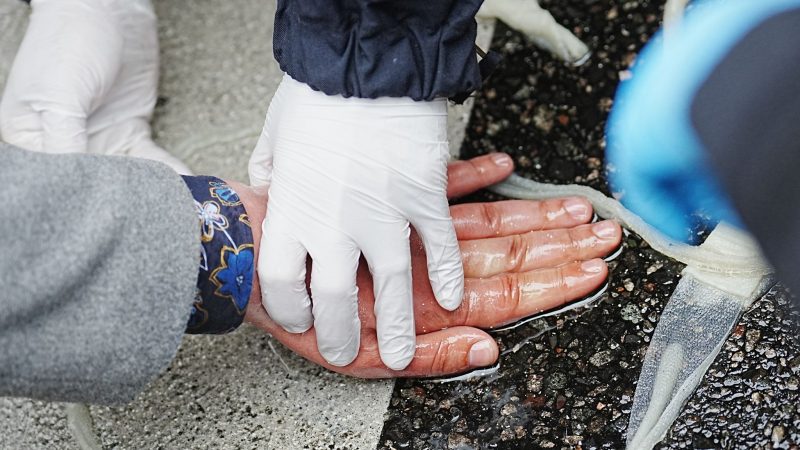 Ein Polizist löst die Hand eines Klimaaktivisten auf einer Straße im Berliner Bezirk Schöneberg mit Speiseöl.