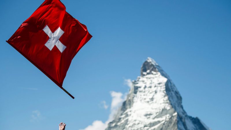 Ein Fahnenwerfer mit der Schweizer Flagge in Aktion vor der Kulisse des Matterhorns.