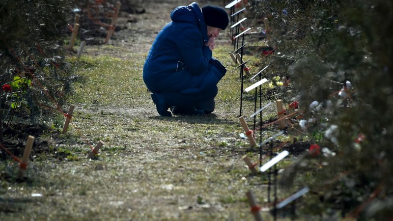 Die Mutter eines russischen Soldaten, der bei einer Militäraktion in der Ukraine getötet wurde, kniet neben einem Baum, der zum Gedenken an ihren Sohn in der Allee der Helden in Sewastopol auf der Krim gepflanzt wurde.