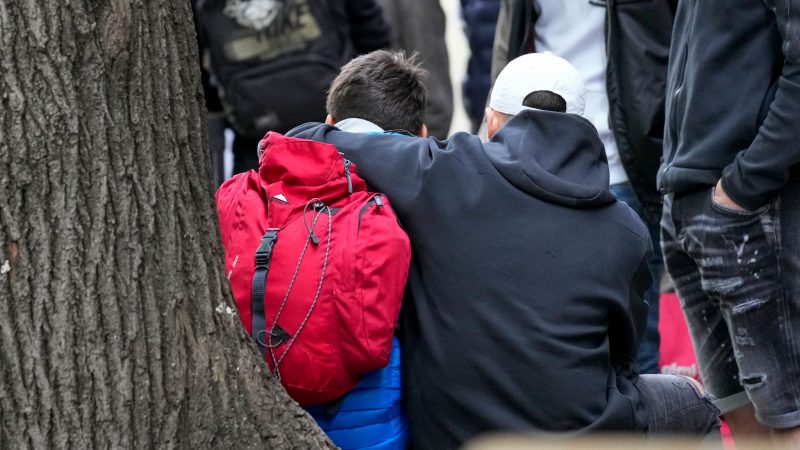 Zwei Kinder nehmen sich in einem abgesperrten Bereich der Schule in den Arm.