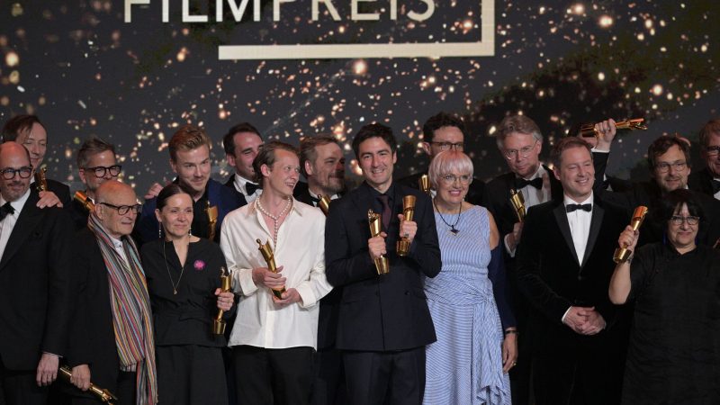 Zusammen mit Kulturstaatsministerin Claudia Roth (im blau-weiß gestreiften Kleid) stehen die Preisträger des Deutschen Filmpreises auf der Bühne.
