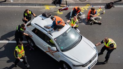 Kurioses Bild: Polizisten müssen ein Auto auf den Standstreifen der A100 in Berlin schieben. Zuvor hatten Aktivisten der Klimagruppe "Letzte Generation" die Straße blockiert.