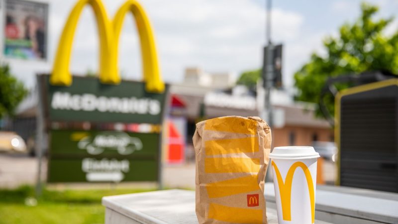 Eine McDonald's To-Go-Tüte und ein dazugehöriger To-Go-Becher stehen vor einer Tübinger McDonald's Filiale.