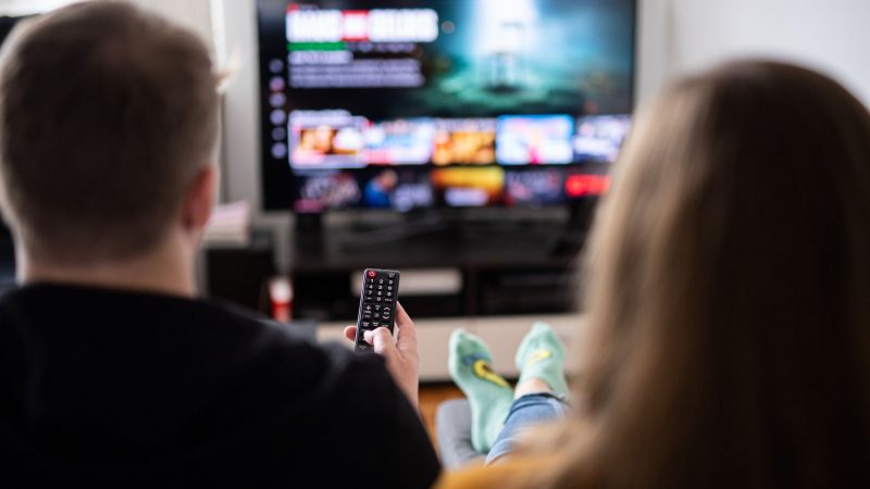 Ein junges Paar sitzt mit einer Fernbedienung vor einem Fernsehgerät. Nachrichten aus dem Fernsehen bleiben für die meisten die wichtigste Quelle. (Symbolbild)