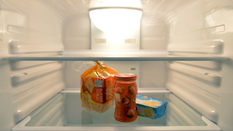 Konfitüre, Toastbrot und Butter stehen in einem Kühlschrank eines Einpersonenhaushalts.
