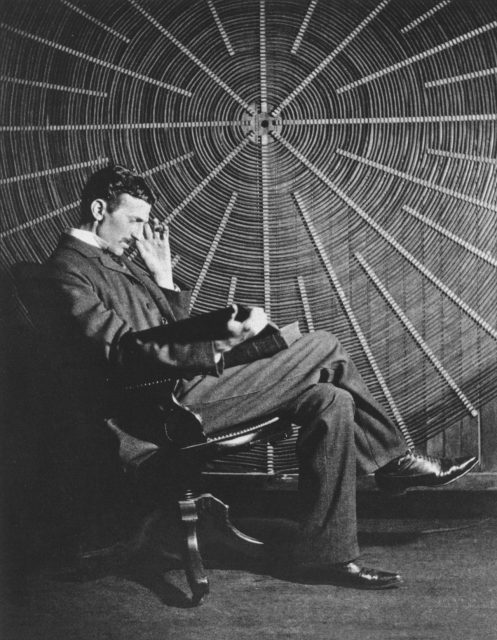Ein nachdenklicher Nikola Tesla mit dem Buch "Theoria Philosophiae Naturalis" von Rudjer Boscovich vor einer Hochvolt-Spule aus seinem Labor in New York.