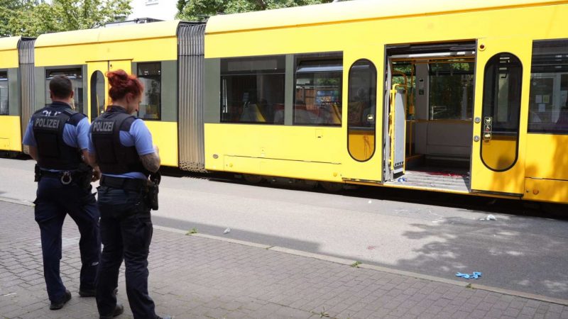 Polizisten stehen vor der Straßenbahn, in der es zu einer Messerattacke kam.