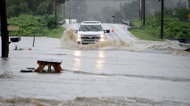 Ein Auto fährt über eine überschwemmte Straße im US-Bundesstaat Vermont. Gouverneur Phil Scott nennt die Situation «historisch und katastrophal».