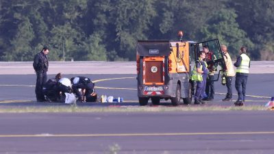 Sicherheitspersonal und Polizisten versuchen am Düsseldofer Flughafen, Aktivisten vom Asphalt auf dem Rollfeld zu lösen.