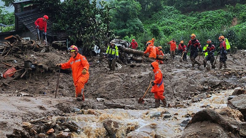 Rettungskräfte suchen  nach Personen in Häusern, die nach durch starken Regen verursachten Erdrutsch eingestürzt sind.