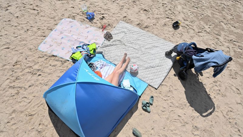 Eine Frau genießt in ihrer Sonnenmuschel das Sommerwetter am Badesee.