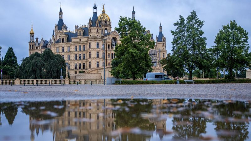 Das Schweriner Schloss, reflektiert in einer Pfütze - ein Kunstwerk, geschaffen durch einen regnerischen Tag.