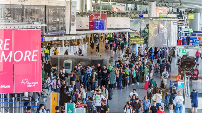 Reisende stehen am Flughafen Frankfurt Main  beim Einchecken in einer langen Schlange.