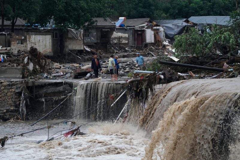Menschen stehen in Peking vor von den Wassermengen zerstörten Häusern. Die extremen Regenfälle sind eine Folge des Tropensturms «Doksuri».