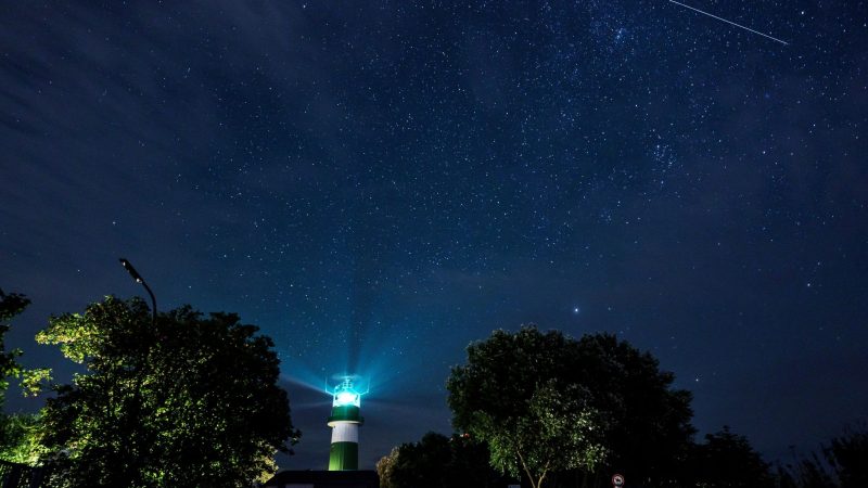 Eine Sternschnuppe zieht über dem Leuchtturm Bülk am Ufer der Ostsee ihre Bahn.