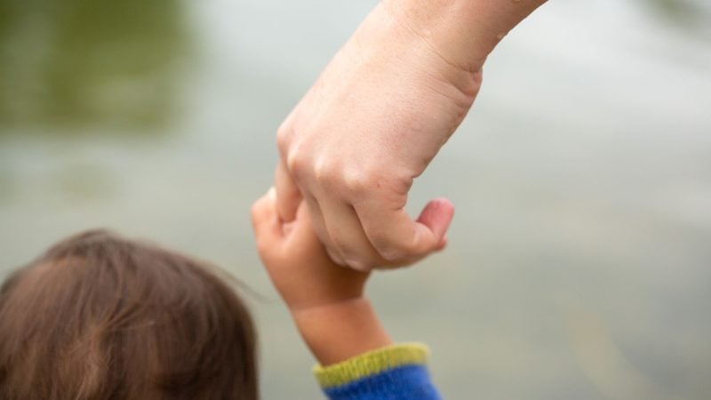 Eine Mutter hält ihr Kind an der Hand.