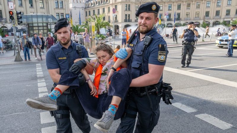 Polizisten tragen auf der Kreuzung am Stachus in der Münchener Innenstadt Aktivisten der Letzten Generation weg. Ihre Aktionen werden teilweise verboten.