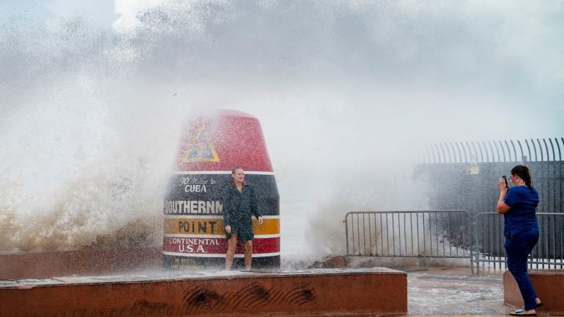 Besucher der Boje am Southernmost Point in Key West trotzen den vom Tropensturm «Idalia» verstärkten Wellen.