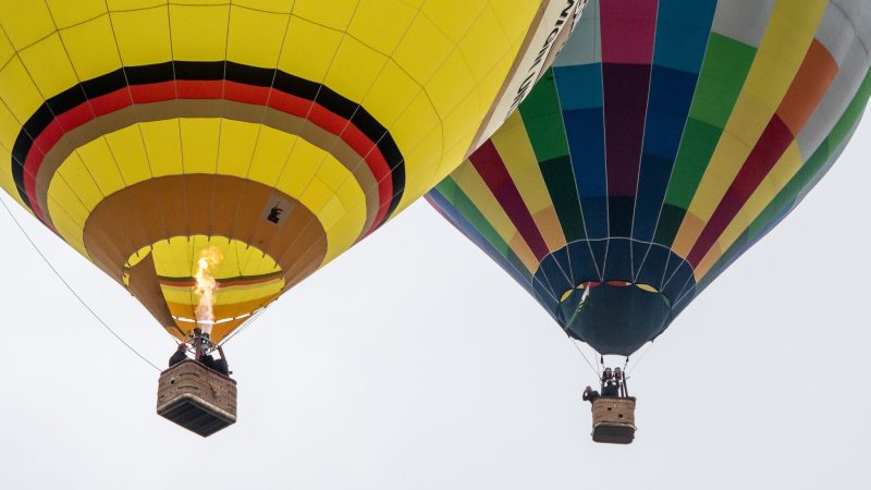 Zwei bunte Heißluftballons steigen bei der Internationalen Warsteiner Montgolfiade in den Himmel. Zum diesjährigen Event werden rund 200 Ballon-Piloten und Pilotinnen aus aller Welt erwartet.