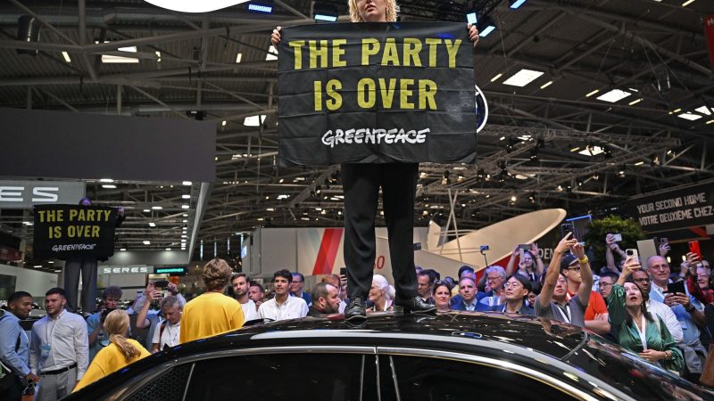 Eine Greenpeace-Aktivistin bei der Eröffnung der IAA auf dem Dach eines ausgestellten Autos.