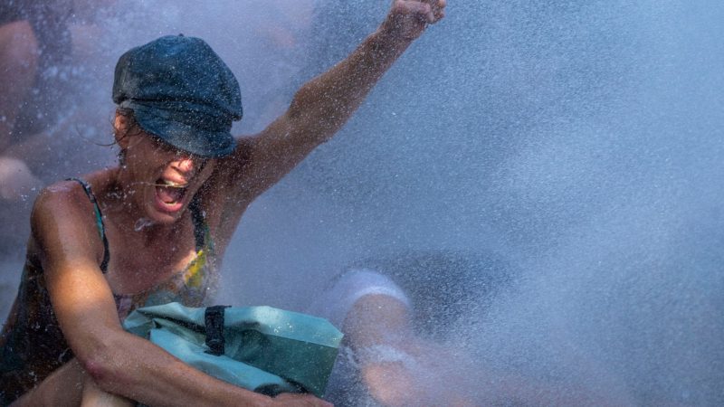 Eine Aktivistin nimmt an einem Klimaprotest der Umweltschutzbewegung Extinction Rebellion in Den Haag teil, während die Polizei Wasserwerfer gegen die Demonstranten einsetzt.