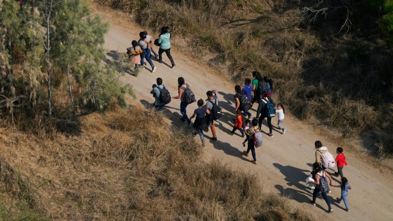 Migranten gehen einen Feldweg entlang, nachdem sie die Grenze zwischen den USA und Mexiko überquert haben.