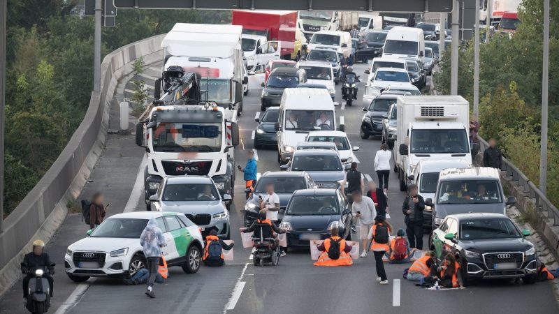 Orangener Protest: Aktivisten stehen während einer Straßenblockade der Klimaschutzgruppe Letzte Generation auf der A100.